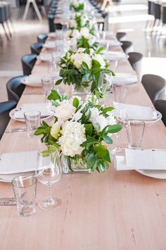 a long table is set with white flowers and place settings