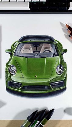 a drawing of a green sports car in front of a computer keyboard and two crayons