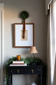 a table with a lamp and pictures on the wall above it in a living room