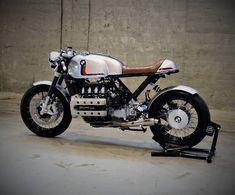 a white and black motorcycle parked in a parking lot next to a cement block wall