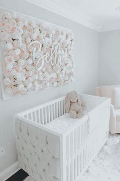 a baby's room with a white crib and pink flowers on the wall