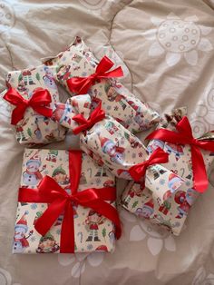 several wrapped presents with red bows on a bed