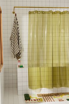 a yellow shower curtain in a bathroom next to a white tiled wall and wooden cabinet