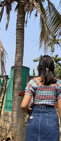 a woman standing next to a palm tree