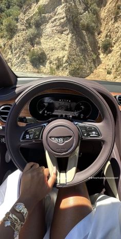 a person driving a car with mountains in the background