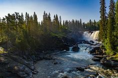 the sun shines on a waterfall and trees