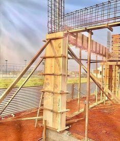 a wooden structure with metal railings on the top and bottom, in front of a building under construction