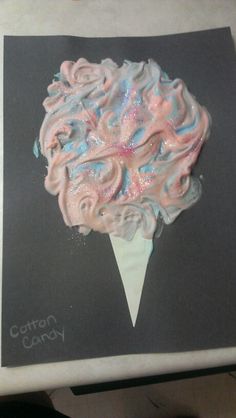 an ice cream cone with pink, blue and white swirls on it sitting on top of a piece of paper