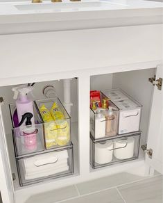 two clear bins are open on the side of a white cabinet in a bathroom