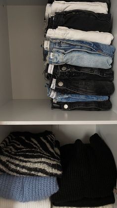 there are many pairs of jeans and sweaters on the shelves next to each other