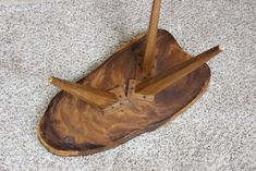 a wooden bowl with two spoons in it on the floor next to a rug