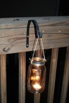 a lantern hanging from the side of a wooden fence with two candles in it,