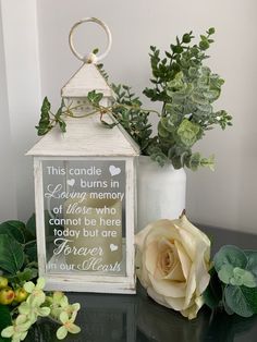 a small white lantern sitting on top of a table next to a vase filled with flowers