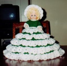 a doll sitting in a dress made out of crocheted yarn on top of a table