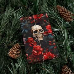 a present wrapped in floral paper with a skull on it and pine cones around it