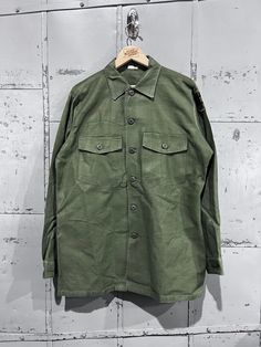 70's OG-107 Fatigue Button Up Shirt- Vietnam War(Army Green)  Great vintage condition. See pictures for condition Dry cleaned and ready to be worn :D 16.5x34. Please review measurements as some vintage items fit smaller than modern sizing. Measurements taken with garment laid flat: 23" across from armpit to armpit 30" length from shoulder to hem 24" sleeve from shoulder to hem Please send a message if you have any questions. Double check measurements and inspect all pictures carefully before pur Retro Khaki Button-up Shirt, Vintage Green Button-up Shirt, Vintage Button-up Camp Shirt With Pockets, Military Style Collared Shirt With Snap Buttons, Vintage Green Camp Shirt With Button Closure, Vintage Camp Shirt With Buttons, Vintage Long Sleeve Camp Shirt With Button Closure, Retro Long Sleeve Khaki Shirt, Vintage Khaki Shirt With Pockets