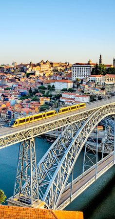 a yellow train traveling over a bridge next to a city