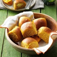 a bowl filled with cornbread rolls on top of a wooden table