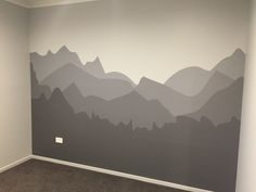 an empty room with mountains painted on the wall and carpeted flooring in front of it