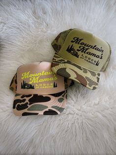 Beige or light green camo foam, high crown, snap and mesh back trucker hat detailed with neon yellow/dark green or brown design Summer Trucker Hat For Camping, Summer Snapback Trucker Hat For Camping, Camouflage Trucker Baseball Cap, Camouflage Trucker Hat With Curved Bill, One Size Fits Most Snapback Hat For Camping, Outdoor Activities 5-panel Trucker Hat, Outdoor Trucker Hat One Size Fits Most, Camping Trucker Hat One Size, Camouflage Baseball Cap Trucker Hat For Camping