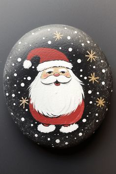 a painted rock with a santa clause on it's face and snowflakes