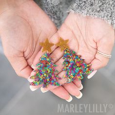 a woman's hands with colorful nail polish and gold glitter christmas trees on them