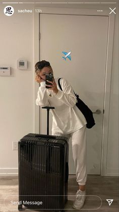 a woman sitting on top of a suitcase taking a selfie