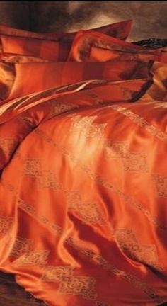 an orange comforter and pillows on a bed