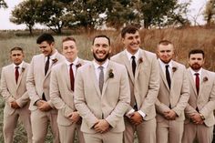 a group of men standing next to each other wearing suits and ties with their hands in their pockets