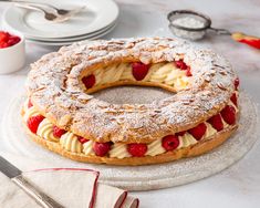 a cake with strawberries and powdered sugar sits on a plate next to other desserts