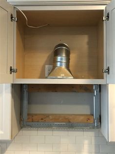 an open cabinet in the kitchen with a light on it's top and bottom shelf