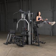 a woman is sitting on a machine in the middle of an exercise room with other equipment