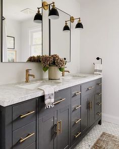 a bathroom vanity with two sinks and three lights on the wall above it, along with an area rug