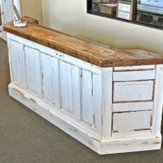 an old white wooden bench with two pictures on the wall behind it in a room