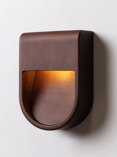 a light that is on the wall next to a white wall with a brown frame