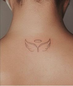 the back of a woman's neck with an angel wing tattoo