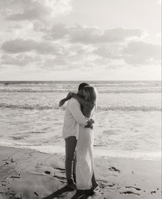 a man and woman hugging on the beach