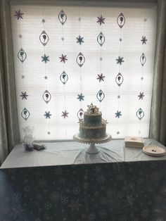 a cake sitting on top of a table next to a window covered in snowflakes