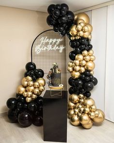 a black and gold balloon arch with happy birthday written on it next to some balloons