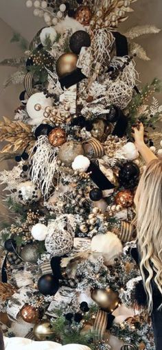 a woman standing in front of a christmas tree with ornaments on it's sides