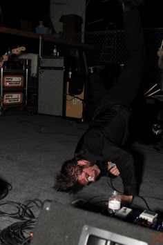 a man is performing on the floor in front of an amplifier and guitar set up