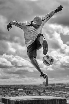 black and white photograph of a man jumping in the air with a soccer ball near his feet