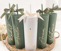 six green and white tumblers with gold lettering on them sitting on a wicker tray