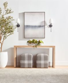 a table with two chairs next to a potted plant on top of it in front of a painting