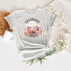 "Embrace the natural beauty and adventurous spirit of Colorado with our \"Colorado\" T Shirt. This cozy shirt is more than clothing; it's a tribute to the breathtaking landscapes and outdoor adventures of the Centennial State. The shirt features a captivating design that pays homage to Colorado's stunning mountains, forests, and outdoor wonders. 🎁 Perfect Souvenir: Whether you're a Colorado native, a visitor, or simply an admirer of this majestic state, this sweatshirt makes a perfect gift or keepsake. PRODUCT KEY The Bella Canva shirt is a unisex light cotton tee, with no side seams, which means there are no itchy interruptions under the arms. : 100% cotton  .: Light and Soft fabric  .: Classic fit Made in USA 100% .: Runs true to size. Remember to go up 2 sizes than your regular to get Adventure Graphic Print Crew Neck Camp Shirt, Graphic Print Crew Neck Camp Shirt For Adventure, Pre-shrunk Relaxed Fit Adventure Shirt, Pre-shrunk Relaxed Fit Shirt For Adventure, Graphic Tee Shirt With Screen Print For Adventure, White Graphic Tee For Outdoor Activities, Pre-shrunk Graphic Tee For Adventure, Colorado Tshirt, Colorado Shirt