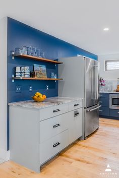 a kitchen with blue and white walls, wooden flooring and stainless steel refrigerator freezer