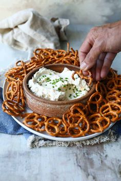 a plate with some pretzels and cream cheese on it, being held by a hand