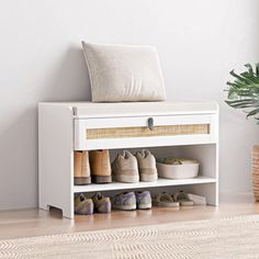 a white shoe rack with shoes on it next to a potted plant and wicker basket