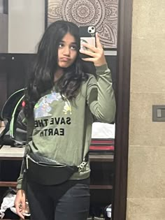 a woman taking a selfie in front of a mirror with the words save the earth on it