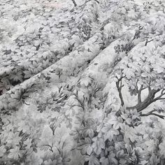 the bed is covered with a black and white flowered bedspread that has trees on it